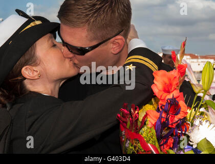 U.S. Navy Lietutenant greets her husband with a kiss at homecoming. Stock Photo