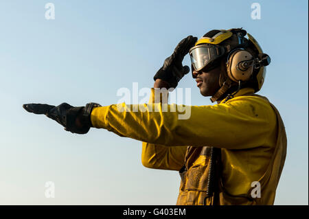 Aviation Boatswain's Mate directs a helicopter on the flight deck. Stock Photo