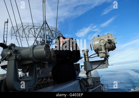 Seaman stands a port lookout watch aboard aircraft carrier USS Theodore Roosevelt. Stock Photo