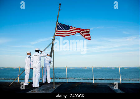 Sailors raise the national ensign on the flight deck of USS Harry S. Truman. Stock Photo