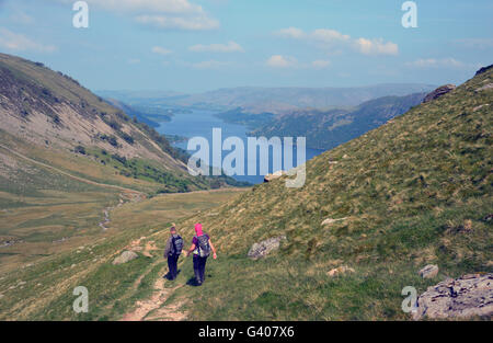 Two Walkers Heading Downhill Towards Ullswater from Nick Head Glencoyne in the Lake District National Park, Cumbria, UK Stock Photo