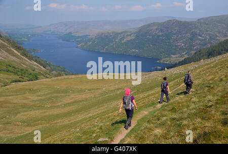 Three Walkers Heading Downhill Towards Ullswater from Nick Head Glencoyne in the Lake District National Park, Cumbria, UK Stock Photo