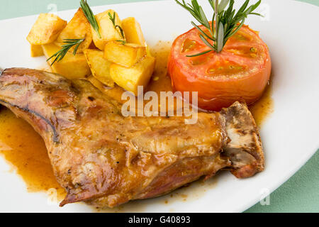 Leg of milk-fed lamb with roasted tomato and chips Stock Photo