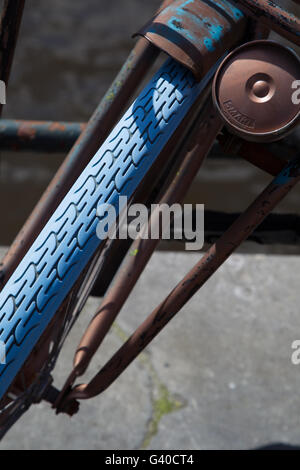 Close up of an old rusty front wheel of a bicycle with a blue tire in downtown Amsterdam, Netherlands.