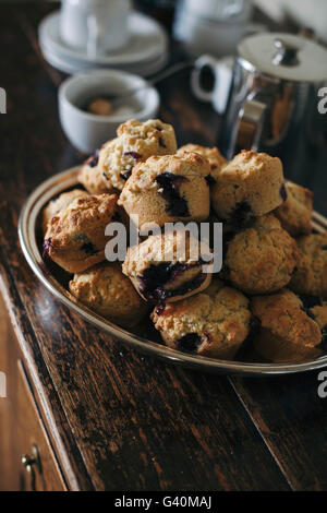 Freshly baked blueberry muffins in a bowl on a rustic wooden cabinet Stock Photo