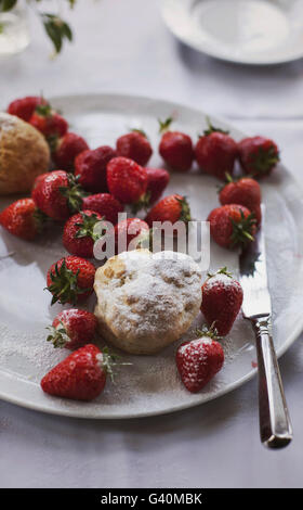 Freshly baked scones and strawberries on a white plate Stock Photo