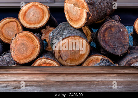 Wood tabletop in perspective view with stack of logs background Stock Photo