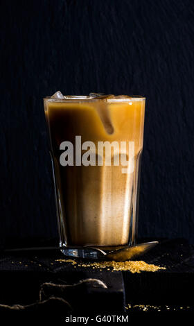 Iced coffee with milk in a tall glass, black background, selective focus Stock Photo