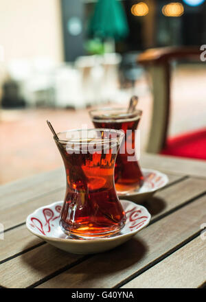 Turkish tea in traditional tulip glasses on table in street cafe, selective focus Stock Photo