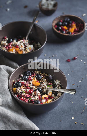 2 bowls of half eaten coconut quinoa porridge with berries and quinoa crunch topping are photographed from the front Stock Photo