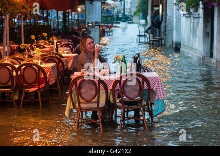 Venice, Italy. 15th June, 2016. A woman eats at the restaurant during the high water on June 15, 2016 in Venice, Italy. The high water in this period is exceptional, and it is a surprise for citizen and tourists.  Credit:  Simone Padovani /Awakening/Alamy Live News Stock Photo