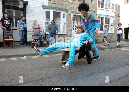 Kington, Herefordshire, UK - Saturday 18th June 2016 - Team shell suit take part in the 40th running of the annual Kington Wheelbarrow Race. Competitors race around the town in the evening and have to stop to drink half a pint of beer at each of the pubs around the town. Stock Photo