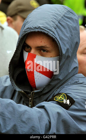 A young man covers his face as he joins a large group of English Defence League members protesting in St George's Square, during their demonstration in Luton this afternoon. Stock Photo