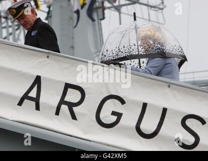The Duchess of Cornwall shelters under an umbrella as the she follows Captain Paul Kehoe along the gangway, after her arrival for a tour aboard the Royal Fleet Auxiliary ship, RFA Argus, to view the facilities and to meet with the staff of the hospital ship, at the Royal Naval Base in Portsmouth. Stock Photo