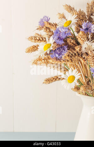 Ripe wheat in white vase on wooden background Stock Photo