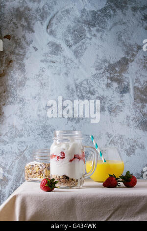 Healthy breakfast muesli, strawberries and yogurt with mango smoothie in glass mason jars. Served with fresh strawberry on white Stock Photo