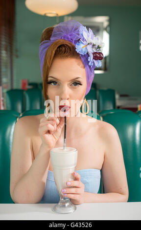 1960s look pin up girl in an American diner drinking a milkshake Stock Photo