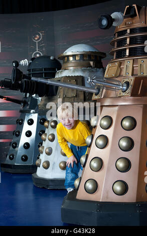 Six year old MacLaine Marshall encounters four generations of the Daleks, (from left) the1984 Dalek from Resurrection of the Daleks, the 1988 Special Weapons Dalek, the 2005 lone Dalek encountered by ninth Doctor and the new Dalek paradigm from 2010, during a sneak preview of The Doctor Who Experience - a fully interactive themed adventure and exhibition which opens at London's Olympia Two venue on Sunday 20th February. Stock Photo