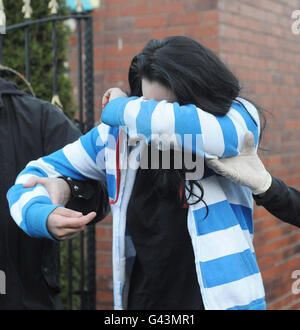 A woman is led away by police officers from a house in Rotherham, South Yorkshire during a joint police and Border Agency operation. Stock Photo