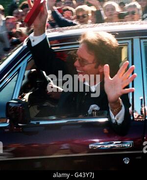 Sir Cliff Richard waves to the crowds as he leaves Buckingham Palace after receiving his knighthood from the Queen at today's (Wed) investiture. Stock Photo