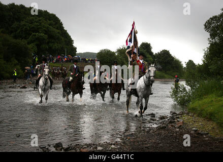 Royal Standard Bearer Rory J. Monks leads riders as they cross a ford on the River Ettrick as they take part in the Selkirk Common Riding, a centuries-old tradition in the royal burgh of Selkirk in the Scottish Borders. Stock Photo