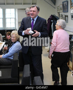 83 year old pensioner May Wilson from Edinburgh touches Shadow Chancellor Ed Balls from behind to offer him some cake after a visit to a pensioners club at Nelson Hall Community Centre in Edinburgh. Stock Photo