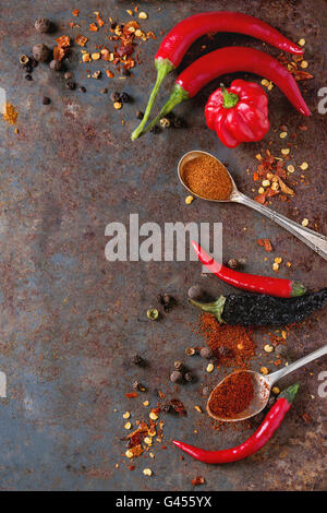 Spicy background with assortment of different hot chili and allspice peppers over old rusty iron background. Top view. With copy Stock Photo