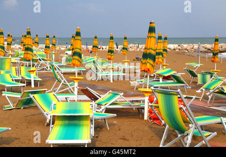 closed Sun umbrellas on sea beach with sun loungers and deckchairs Stock Photo