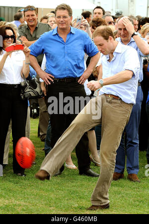 Prince William kicks an Australian rules football towards a group of photographers during a visit to the Murrabit Football ground in southern Australia, on the last day of his visit to New Zealand and Australia. Stock Photo