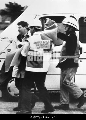 A blanket clad survivor carried by ambulance men on his arrival at Aberdeen after the explosion disaster on board the North Sea Oil production platform Piper Alpha. Stock Photo