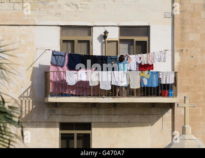 A woman hangs her washing on a line on her balcony Stock Photo