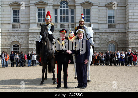 Captain Anton Lin from Blues and Royals of the Household Cavalry (left) and Captain Le Blay from the French Garde Republicaine (right) pose on horseback as Major General Cubitt GOC (2nd left) and French Attache Admiral Charles-Edouard de Coriolis (2nd right) shake hands in Horse Guards, London where it was announced that French armed forces will join British servicemen in the annual Royal Tattoo in the grounds of Windsor Castle in May. Stock Photo