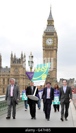 Unison general secretary Dave Prentis carries a for sale sign on Westminster Bridge, with 'estate agents Cameron, Clegg & Lansley' during an NHS cuts protest by the public sector union outside Guys and St Thomas' Hospital, London.