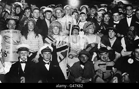 A fancy dress ball restricted to officers and men serving aboard the Bellerophon Class battleship HMS Temeraire, which is now being used as a cadet training ship (seagoing). Prince George, who was the 'Belle of the Ball' is seated in the centre row just under Britannia's trident. Stock Photo