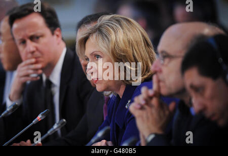British Prime Minister David Cameron listens to U.S. Secretary of State Hillary Clinton speak at the opening of the Libyan Conference in London.
