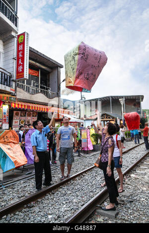 Shifen, Taiwan - July 15, 2013: Tourists releasing a decorated sky lantern in Shifen, a local tradition. Stock Photo