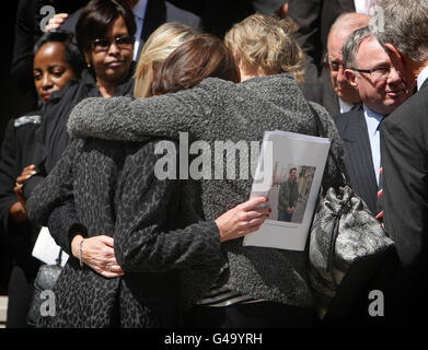 Mourners comfort each other after the funeral of photographer Tim Hetherington, who was killed in a mortar attack in Libya, at the Church of the Immaculate Conception in Mayfair, London. Stock Photo