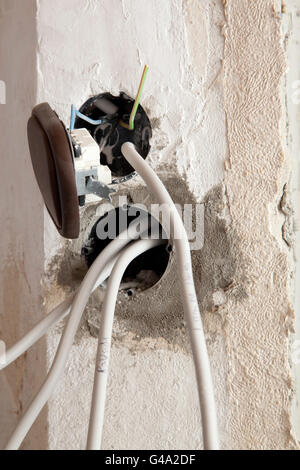 Power outlets with power cables and a light switch hanging out, electrical installation, renovation of an apartment Stock Photo