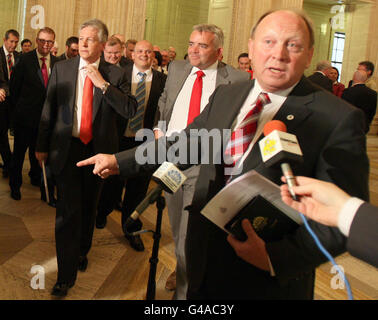 First Minister, Peter Robinson, (left) moves forward to talk to the media, as Unionist Jim Allister (right), Leader of the TUV, and new Assembly member, conducts a media interview in the great hall at Stormont, Belfast.