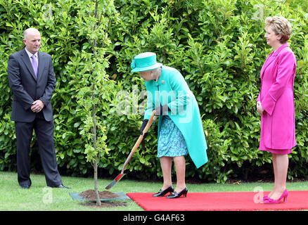 Britain's Queen Elizabeth II plants a tree in the grounds of Aras an Uachtarain (The Irish President's official residence) in Phoenix Park, Dublin, as Irish President Mary McAleese looks on. Stock Photo