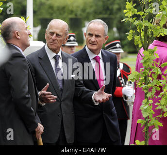 The Duke of Edinburgh speaks with Dr Martin McAleese (right) and Robert Norris (left), head gardener at Aras An Uachtarain in Phoenix Park, Dublin whilst Britain's Queen Elizabeth II plants a tree. Stock Photo