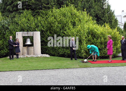 Britain's Queen Elizabeth II plants a tree in the grounds of Aras an Uachtarain (The Irish President's official residence) in Phoenix Park, Dublin, as Irish President Mary McAleese looks on. Stock Photo