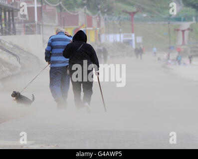 Visitors to Scarborough cover their faces as gale force winds blow up a sand storm on the North Bay and promenade as gales and severe gales affect the Northern part of the UK. Stock Photo