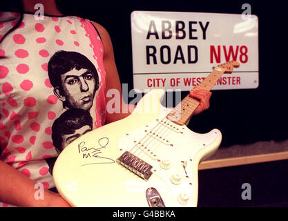 An original 1960's sleeveless 'Beatles' dress printed with facial portraits of the four members of the band, a Fender Squier Stratocaster electric guitar signed by Paul McCartney and an unused enamel street sign for the road their recording studio made famous - Abbey Road in north London - on show at Christie's Auction House in London today (Tuesday) ahead of their sale on April 30th. Photo by Ben Curtis/PA