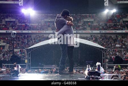 Enrique Iglesias hugs fan Sophie Elphick, 18, on stage during Capital FM's Summertime Ball at Wembley Stadium, London. Stock Photo