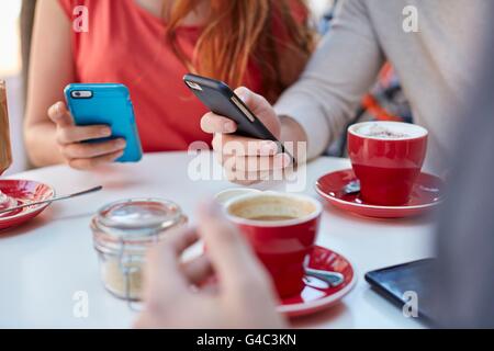 MODEL RELEASED. Young people in cafe using smartphones. Stock Photo