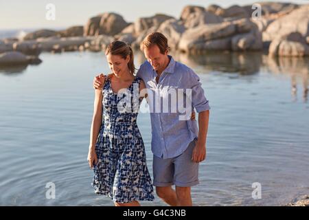 MODEL RELEASED. Couple paddling in the sea, man with arm around woman. Stock Photo