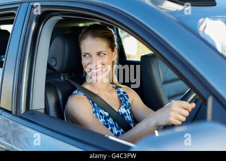 MODEL RELEASED. Young woman looking through car window, smiling. Stock Photo