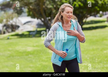 MODEL RELEASED. Senior woman exercising, holding her chest in pain. Stock Photo