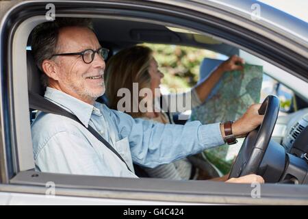 MODEL RELEASED. Senior man in car, woman holding map. Stock Photo